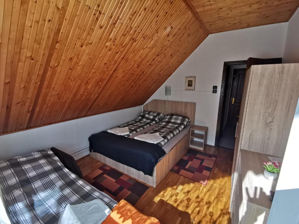 1 dormitorio con cama y techo de madera en Country Vendégház, en Szilvásvárad