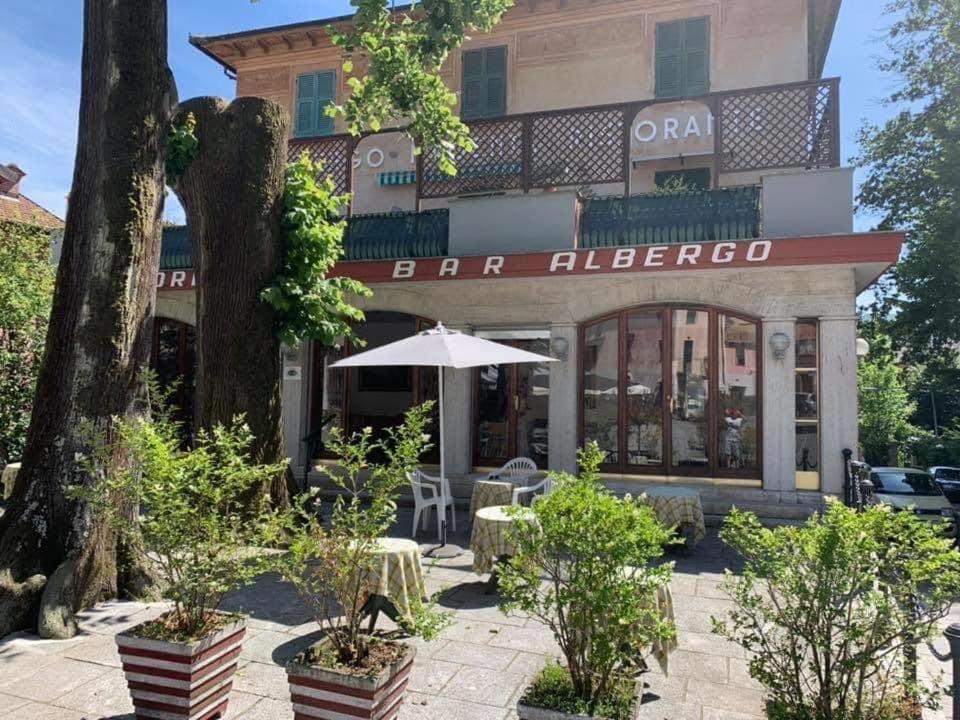 un caffè con ombrellone di fronte a un edificio di Albergo Magenta a Casella