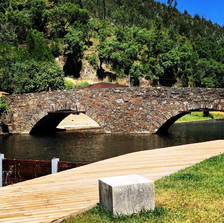 eine Steinbrücke über einen Wasserkörper in der Unterkunft Casa da Ribeira Guesthouse in Alvares