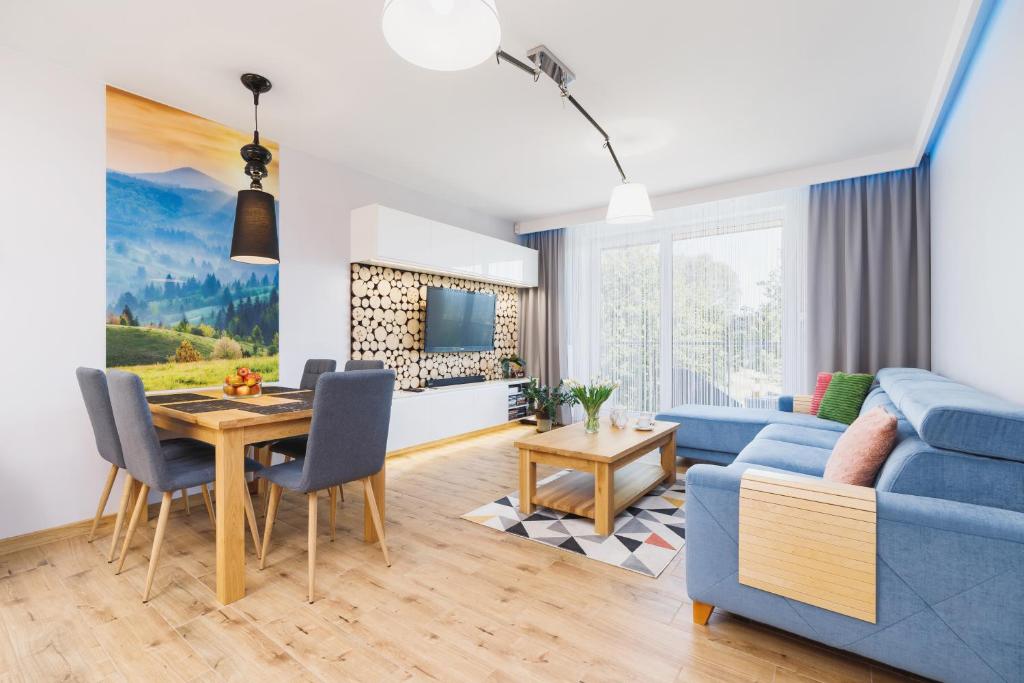 a living room with a blue couch and a table at DreamView Premium Apartment Wisła Kamienna by Renters in Wisła