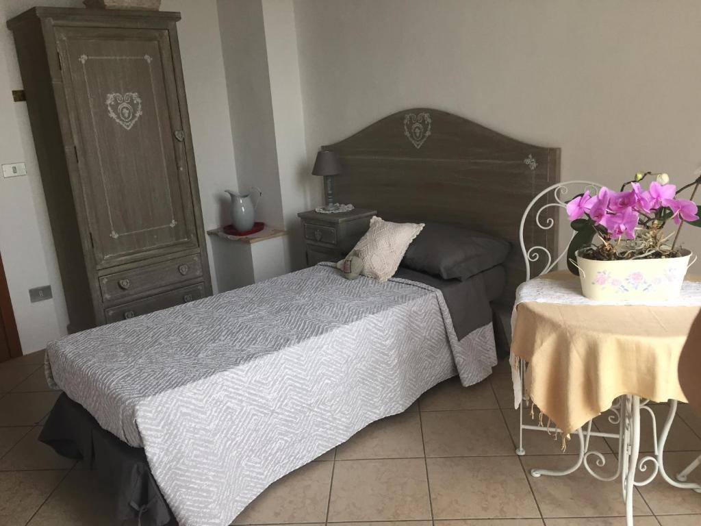 1 dormitorio con 1 cama y 1 mesa con una maceta de flores en B&B Il moro selvatico, en Poviglio