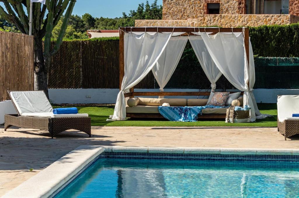 a pool with a canopy and chairs and a couch next to a pool at Cas garrovers in Can Furnet
