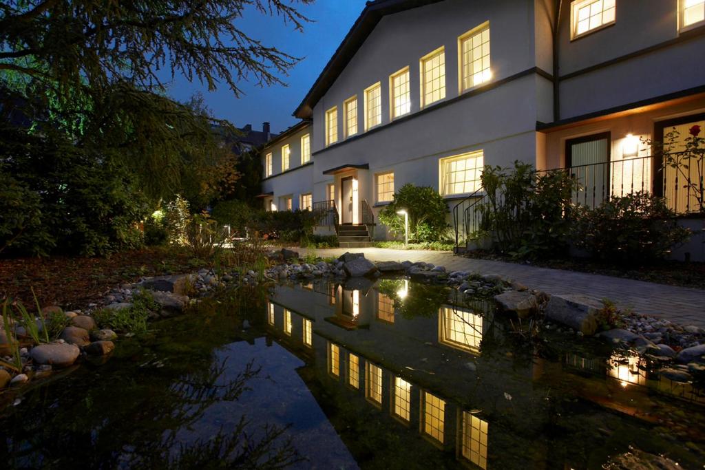 uma casa com um lago em frente em Hotel An der Gruga em Essen