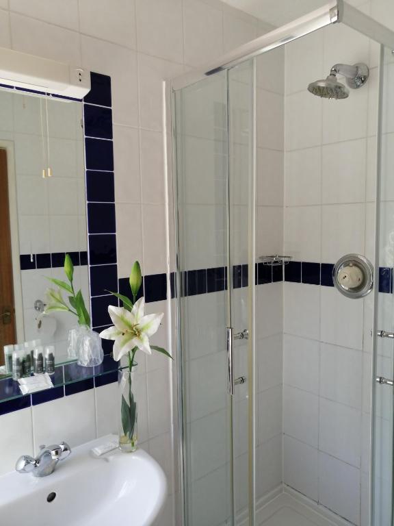a bathroom with a sink and a shower with a vase of flowers at The Tudor Hotel in Harrow