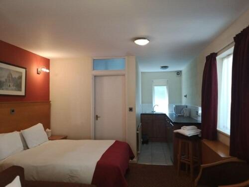 a hotel room with a bed and a kitchen at The Tudor Hotel in Harrow