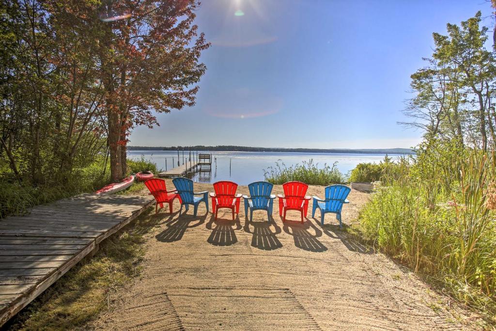 a group of chairs sitting on a dock near the water at Interlochen Home on Green Lake with Dock and Beach! in Interlochen