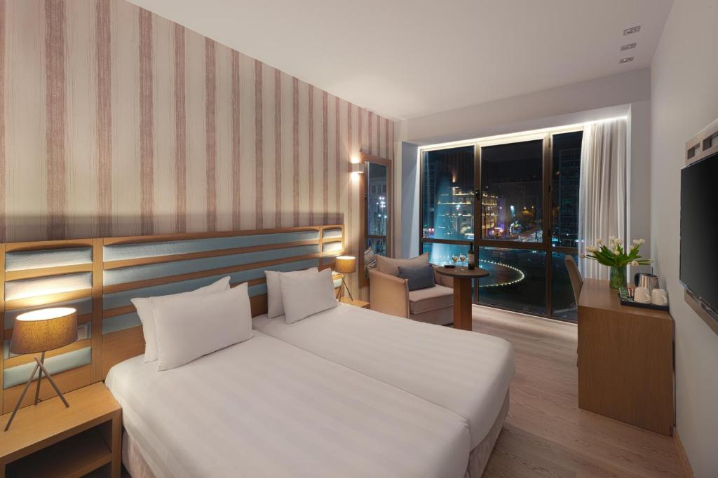 a bedroom with a large bed and a large window at Athens Tiare by Mage Hotels in Athens