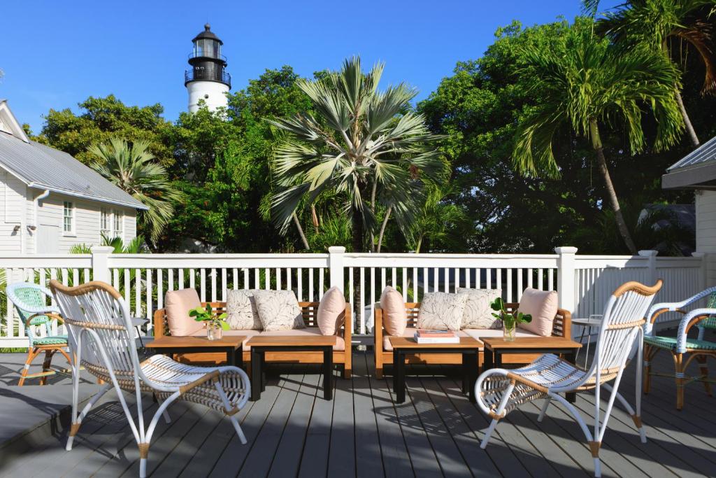 een terras met een houten tafel en stoelen en een vuurtoren bij Lighthouse Hotel - Key West Historic Inns in Key West