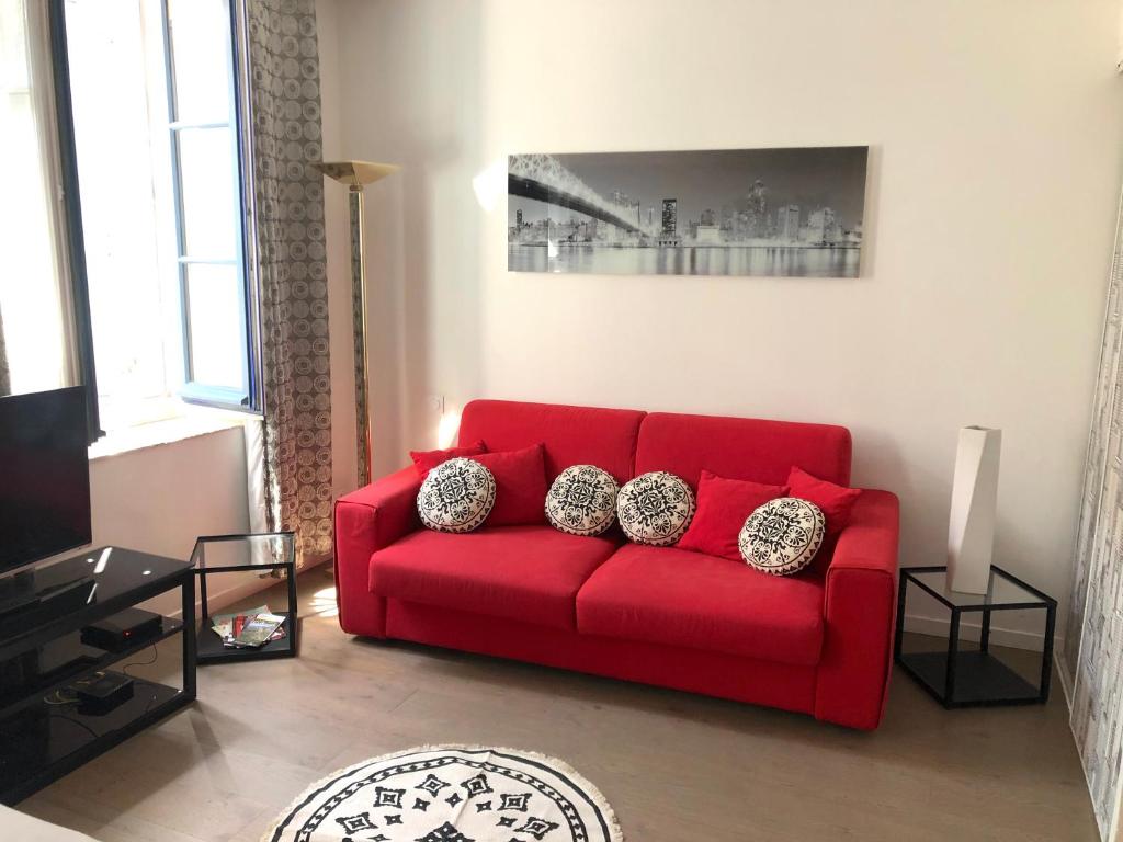 a red couch with pillows in a living room at Gîte de La Cité in Carcassonne