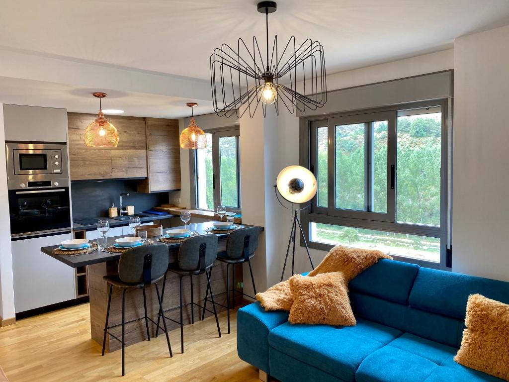 sala de estar con sofá azul y cocina en Prime Loft PIRINEOS, en Sabiñánigo