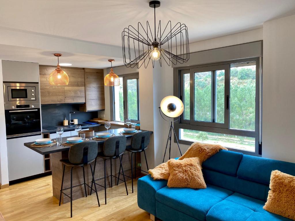 uma sala de estar com um sofá azul e uma cozinha em Prime Loft PIRINEOS em Sabiñánigo
