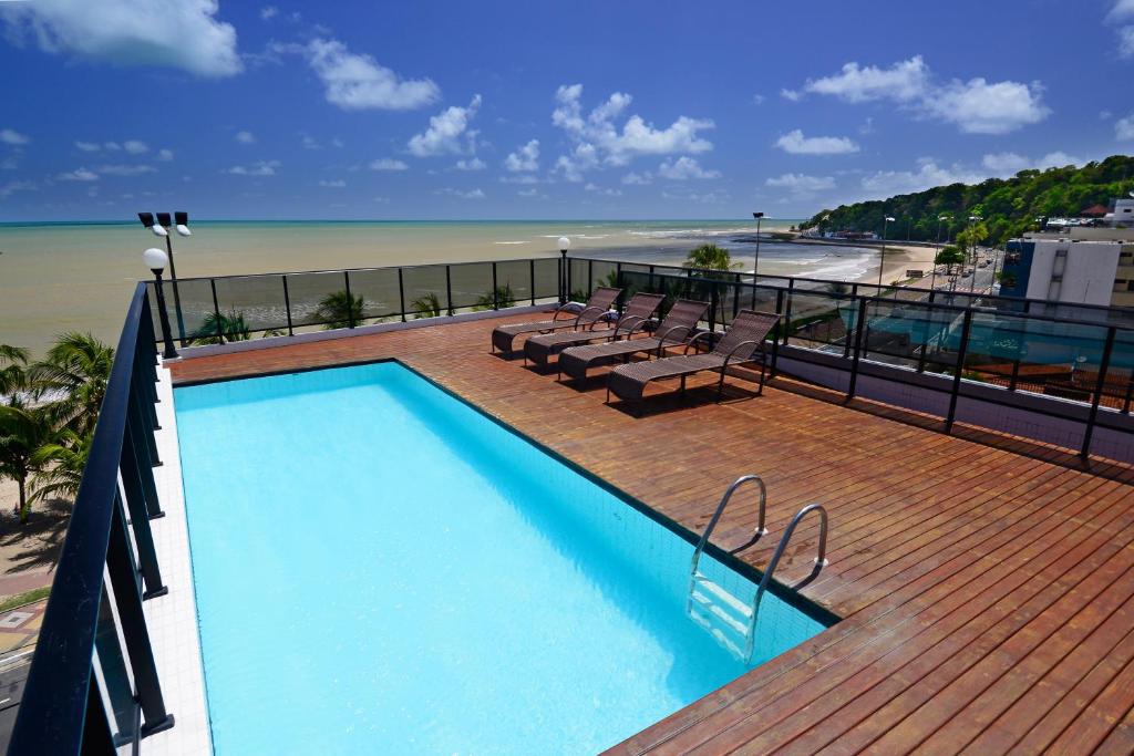 a swimming pool on a deck next to the beach at Nobile Inn Cabo Branco in João Pessoa