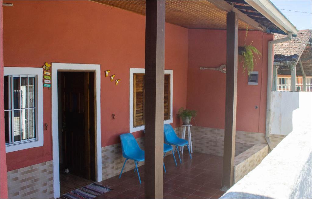 a porch of a house with two blue chairs at Casa do Carlos, praia da Enseada Ubatuba-SP in Ubatuba