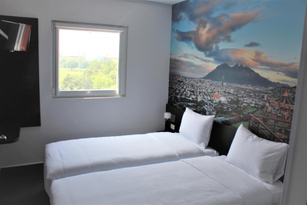 a bedroom with two beds and a window at Hotel Hi! Fundidora in Monterrey