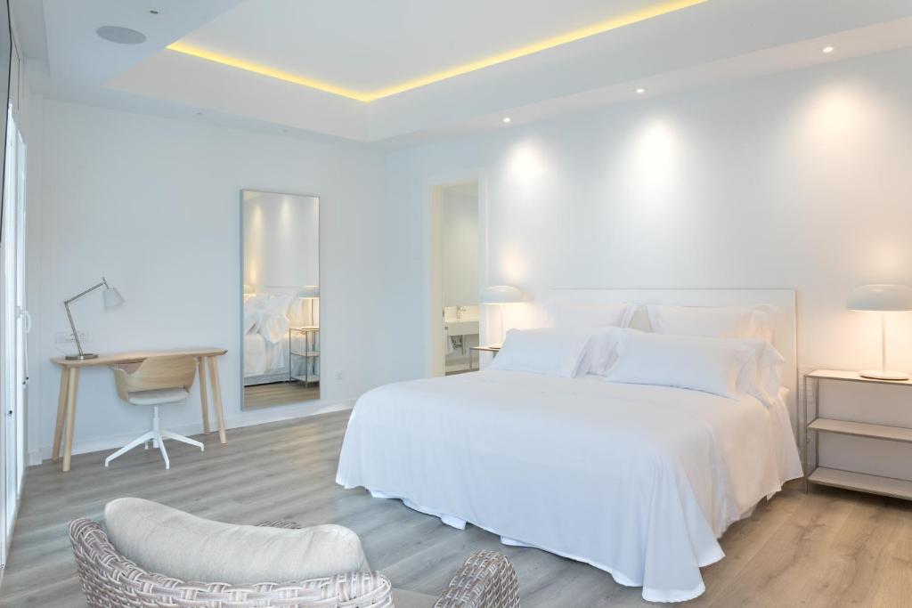 a white bedroom with a white bed and a desk at Lauser City Suites in Los Llanos de Aridane