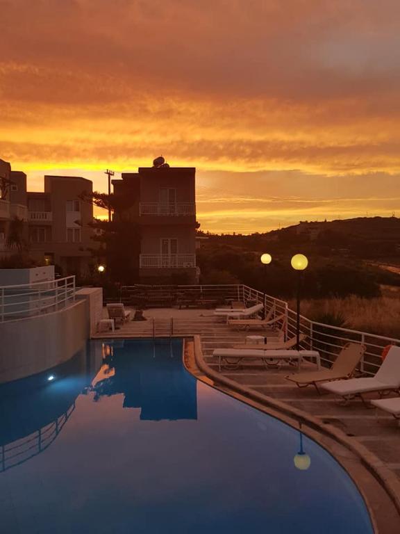 a large swimming pool with a sunset in the background at Pelagia Bay Hotel in Agia Pelagia