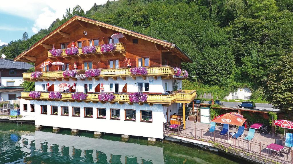 a building on the water with flowers on it at Hotel-Garni Seestrand in Zell am See