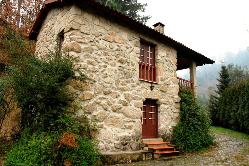 Casa de piedra antigua con ventanas rojas y porche en Casa Da Peneda, en Gerês