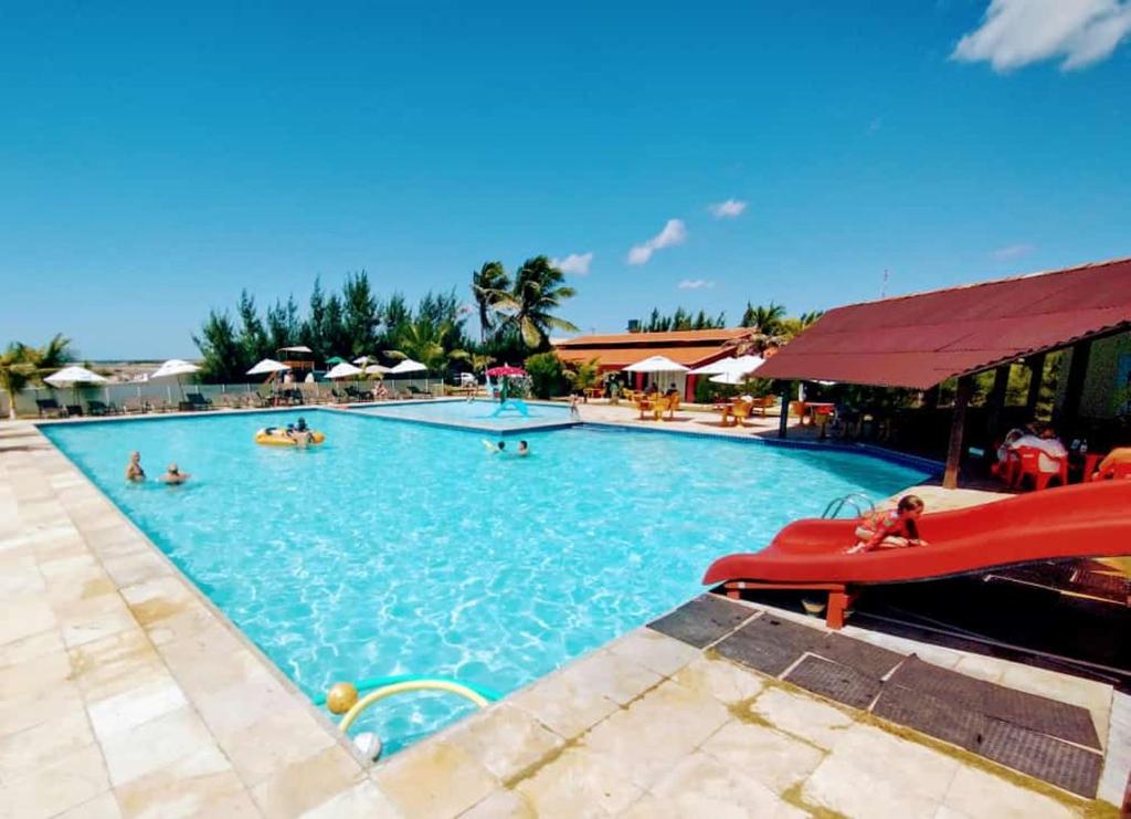 a large swimming pool with people in the water at Hotel Vila Jardim in Parajuru