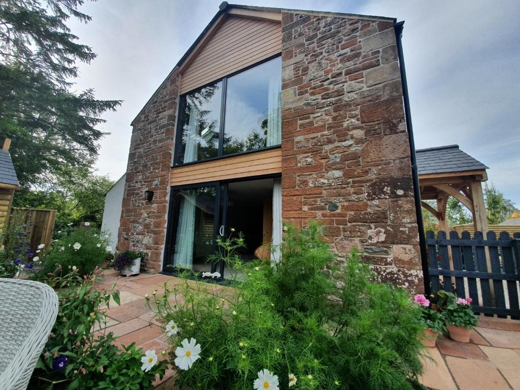 uma casa de tijolos com janelas de vidro num pátio em Dandelion Cottage em Carlisle