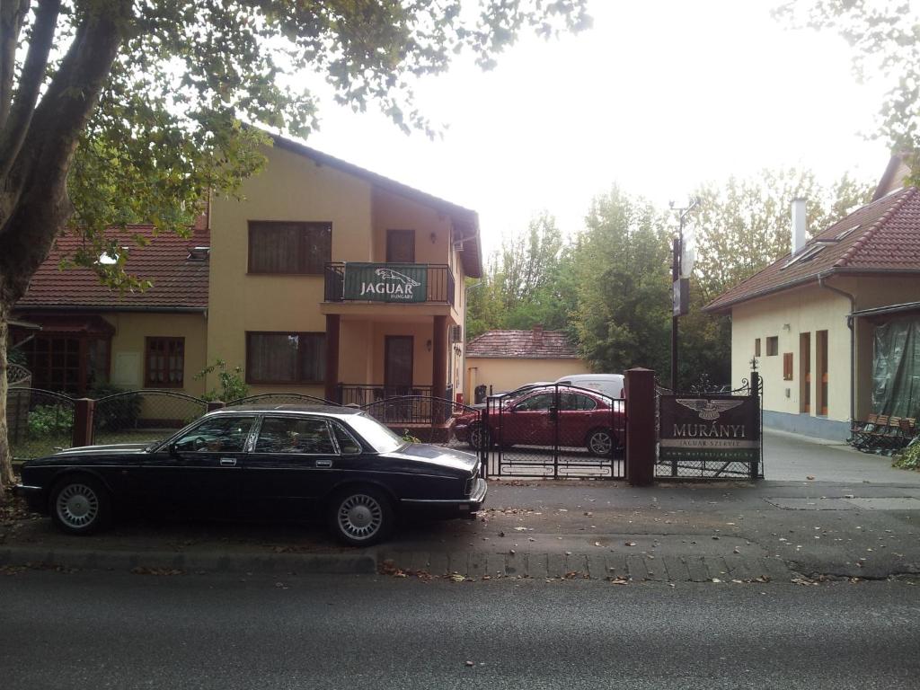 a black car parked in front of a house at Balaton Apartmanház in Siófok