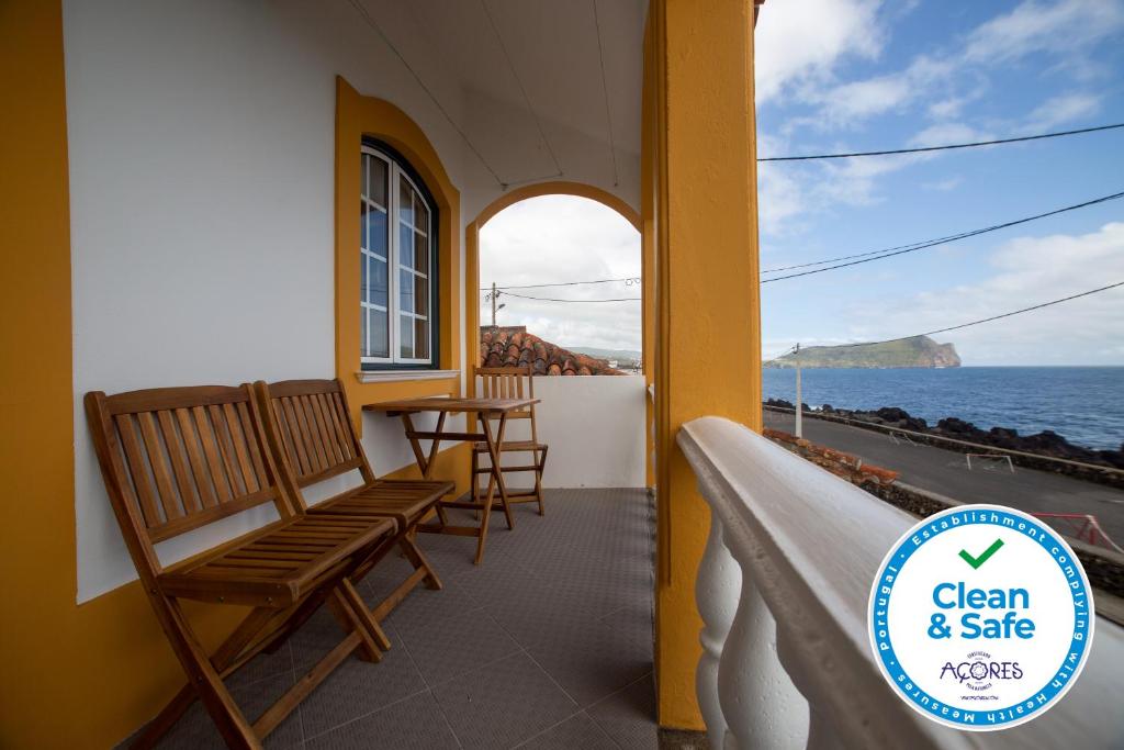 Un balcón con sillas y vistas al océano. en Casa das Arcadas, en Angra do Heroísmo