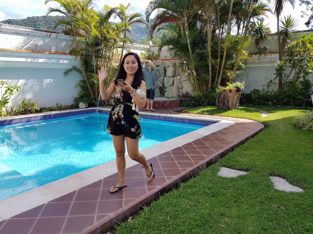 a woman is standing next to a swimming pool at Perla Maya Hotel in Panajachel