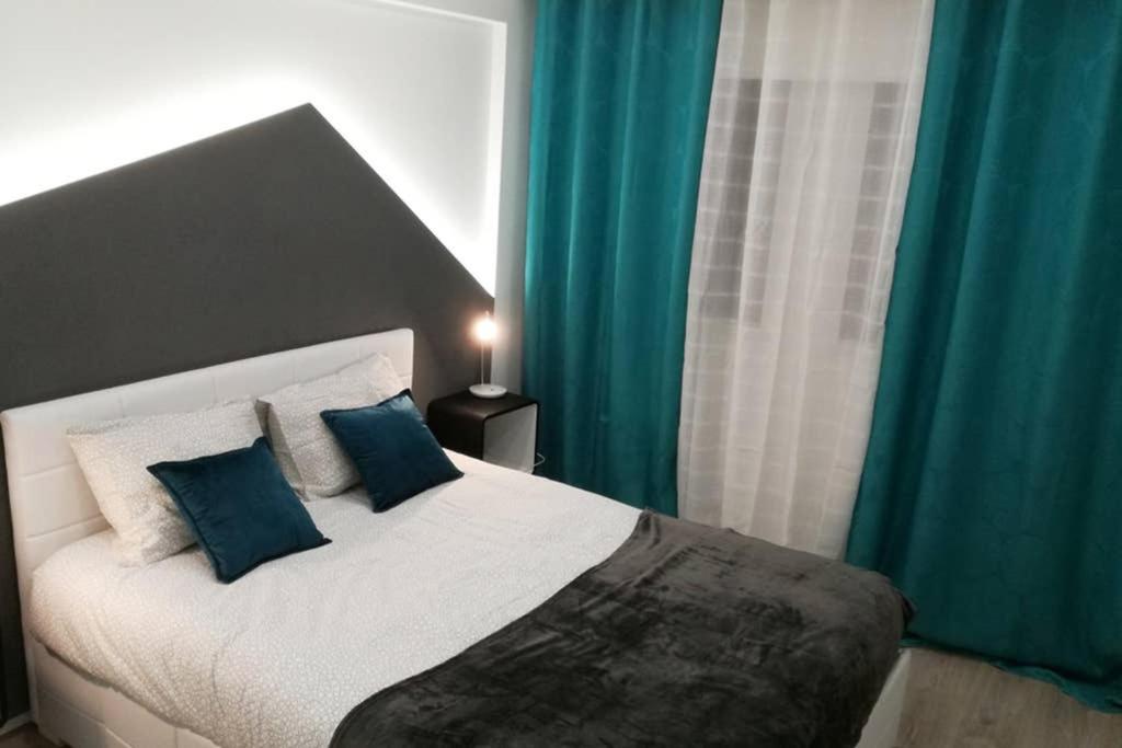 a bedroom with a large bed with blue curtains at Ria Center Apartment - Right in Faro