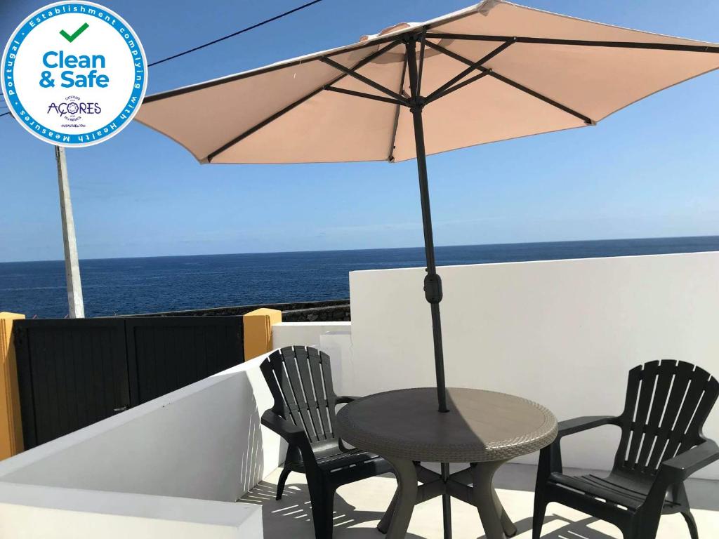 a table and chairs with an umbrella on a balcony at Casa Branca in Angra do Heroísmo