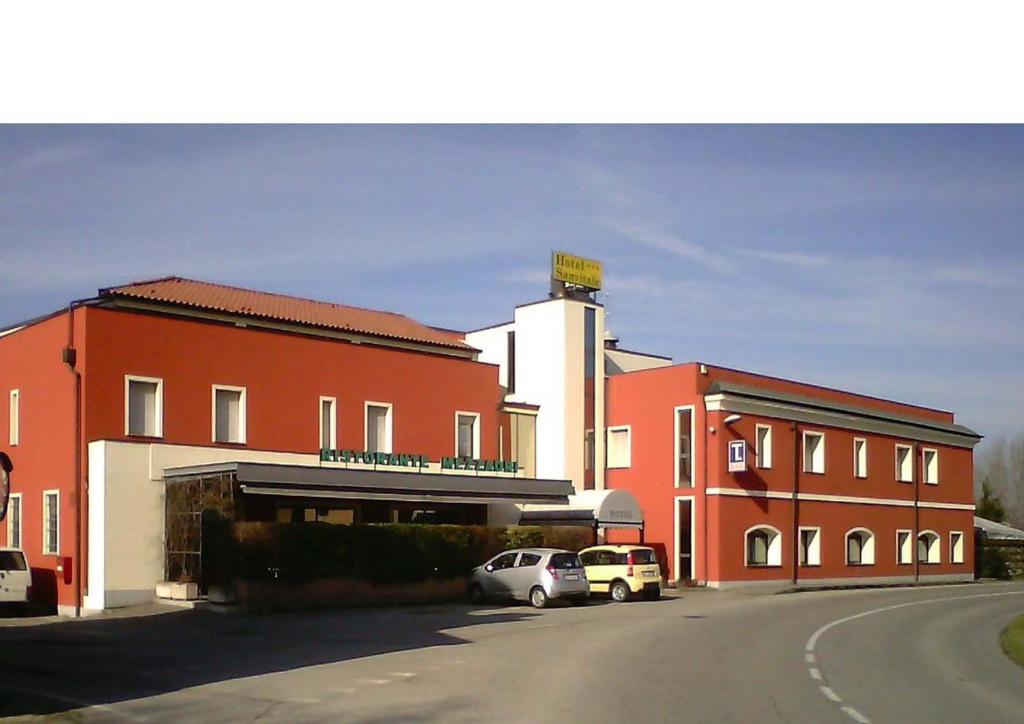 a building with two cars parked in a parking lot at Hotel Sanvitale in Fontanellato