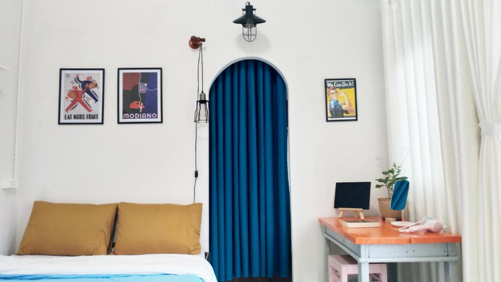 a bedroom with a blue curtain next to a desk at Sophie Studio in Da Lat