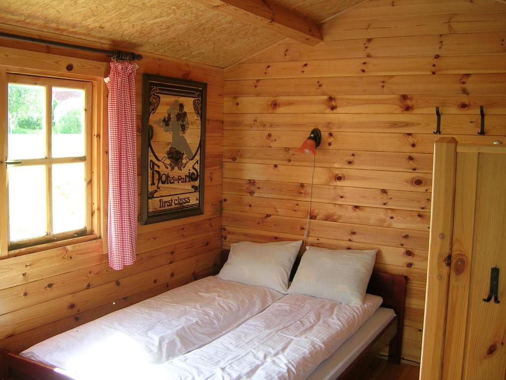Ce lit se trouve dans une cabane en rondins dotée d'une fenêtre. dans l'établissement Chalet, à Myza Igaste