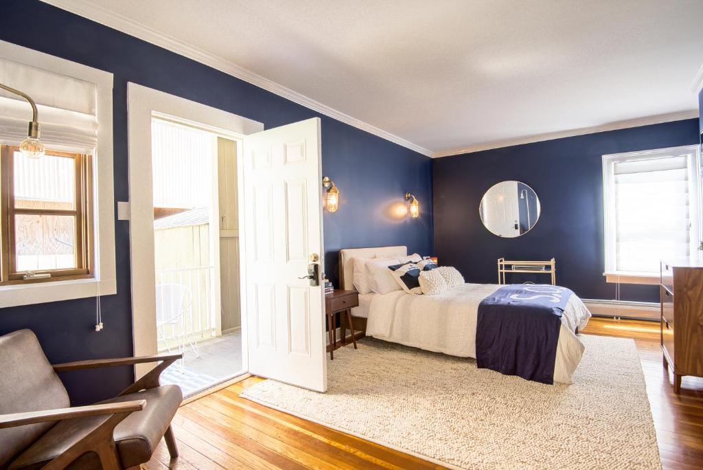 1 dormitorio con paredes azules, 1 cama y espejo en Nautical Nest Hudson en Hudson