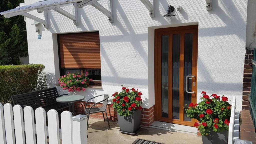 a white house with a bench and a door and flowers at Ferienwohnung Riemeyer in Lutherstadt Wittenberg