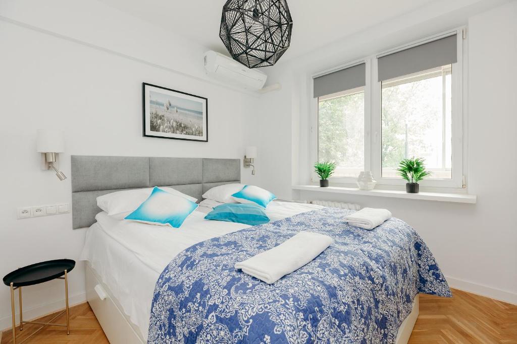 ein weißes Schlafzimmer mit einem großen Bett mit blauen Kissen in der Unterkunft ShortStayPoland Jana Pawła (B27) in Warschau