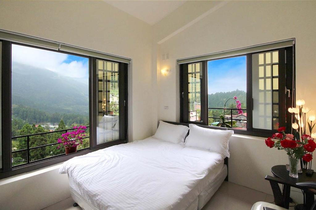 sypialnia z łóżkiem i dwoma dużymi oknami w obiekcie Shan Lan B&B w mieście Fenchihu