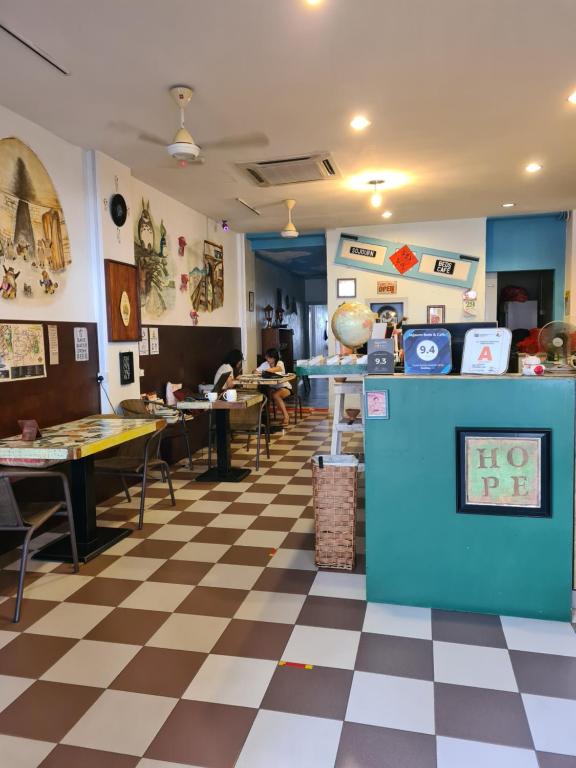 
a room with a table, chairs, and a refrigerator at Sojourn Beds & Cafe in Taiping

