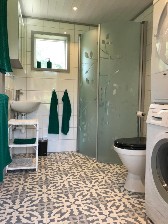 een badkamer met een douche, een toilet en een wastafel bij Mysig nybyggd stuga nära hav och natur in Klövedal