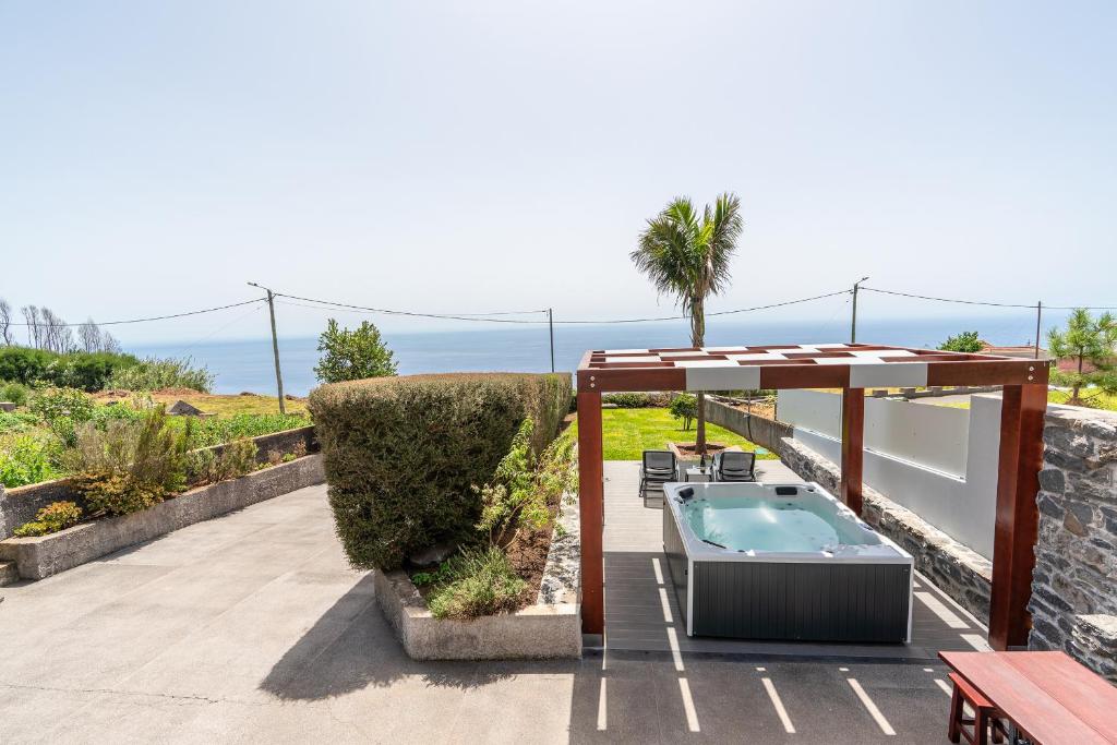 een patio met een hot tub en een parasol bij Casa Leonor by Rent2U, Lda in Arco da Calheta