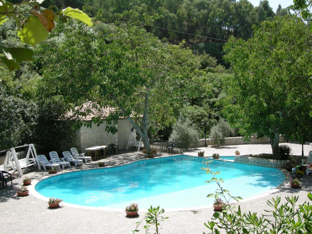 a large blue swimming pool with chairs and trees at 'A Cunziria in Vizzini