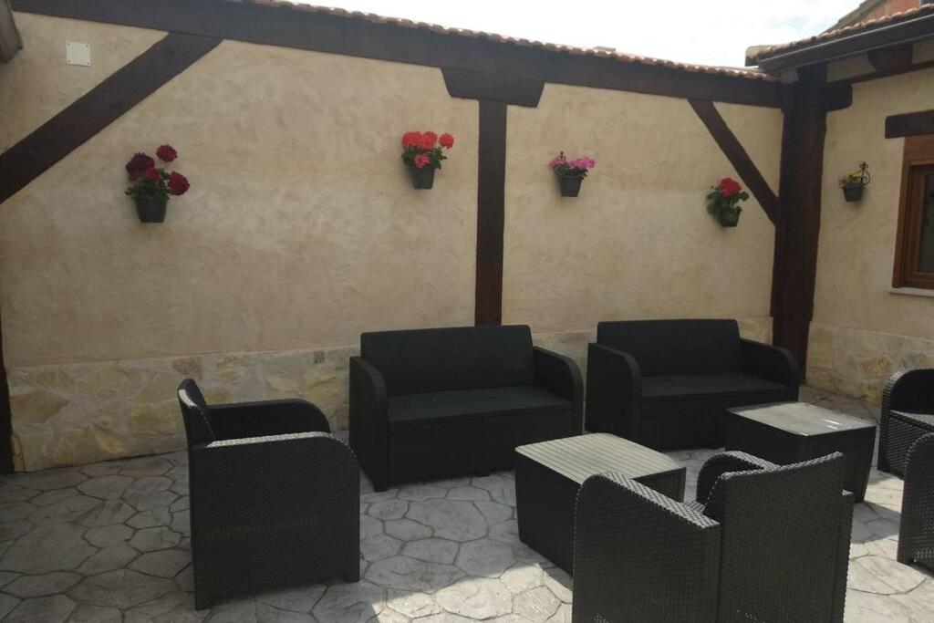 Villalba de Adaja的住宿－Casa Rural Ruplas II，庭院设有黑色的椅子和桌子,种有鲜花