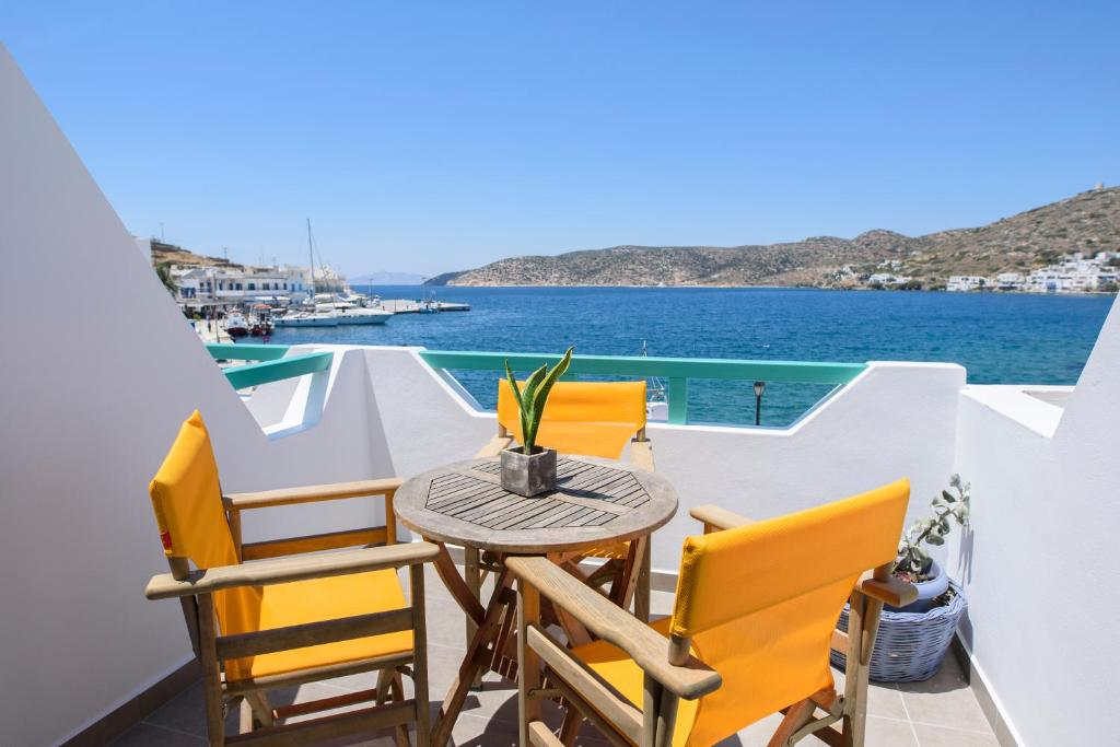 balcone con tavolo e sedie affacciato sull'acqua. di Porto Katapola Pension a Katápola