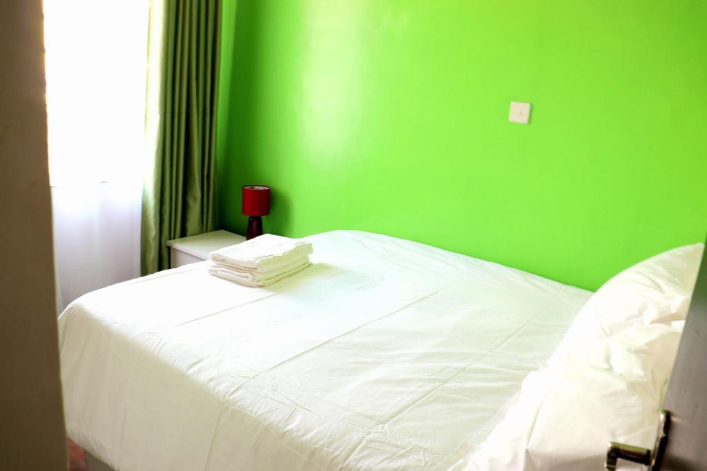 una camera verde con un letto bianco con una parete verde di Little Green Room Homestay near JKIA Airport & SGR Railway Station a Nairobi