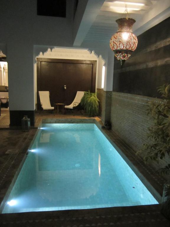una grande piscina in una stanza con lampadario a braccio di Riad Amin a Marrakech