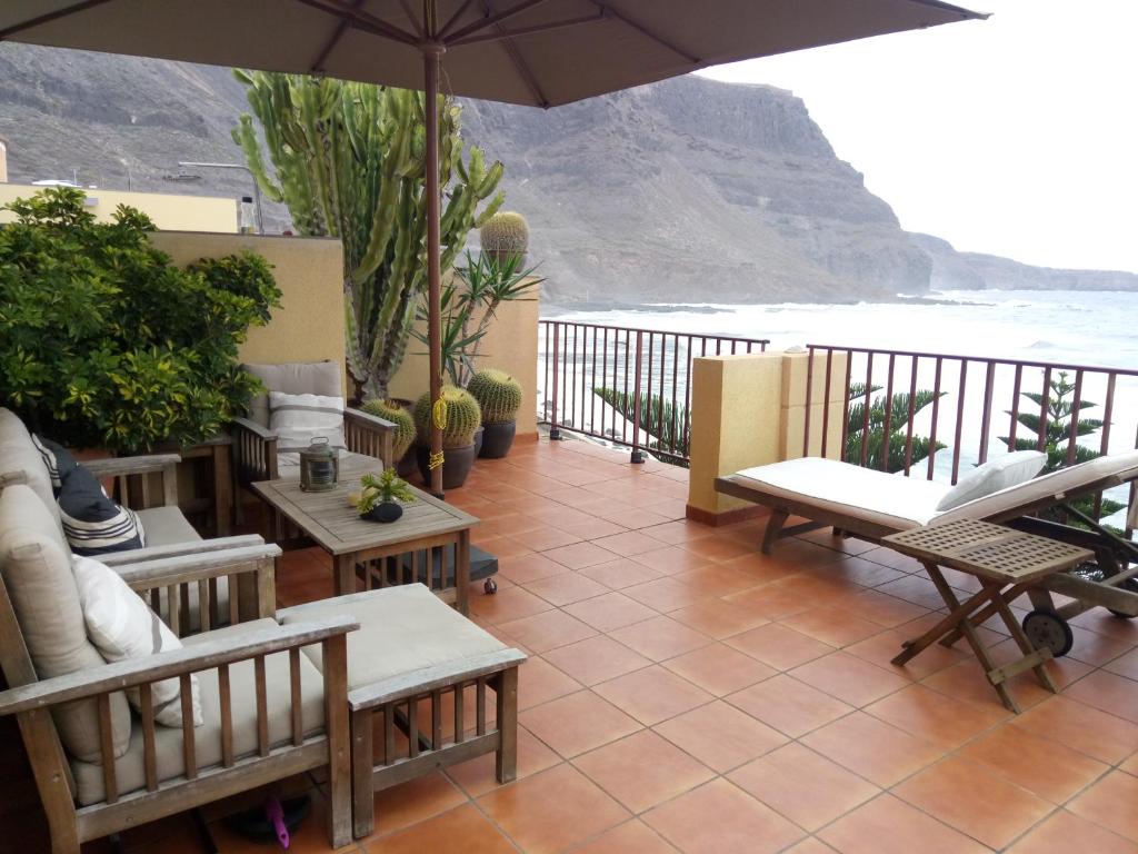 a patio with tables and chairs and an umbrella at Facing the ocean in Santa Maria de Guia de Gran Canaria