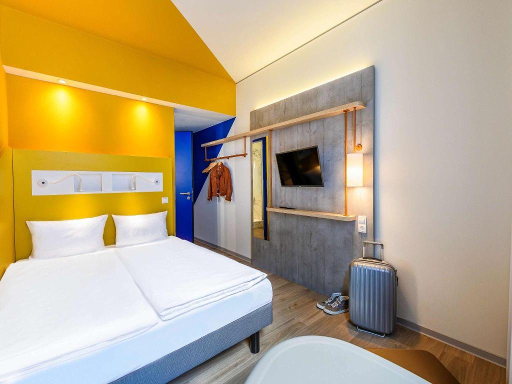 a hotel room with a bed and a suitcase at ibis budget Bremen City Center in Bremen