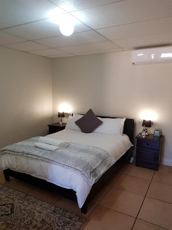 um quarto com uma cama com duas mesas de cabeceira e dois candeeiros em CHEETAH MANOR #2 em Bloemfontein