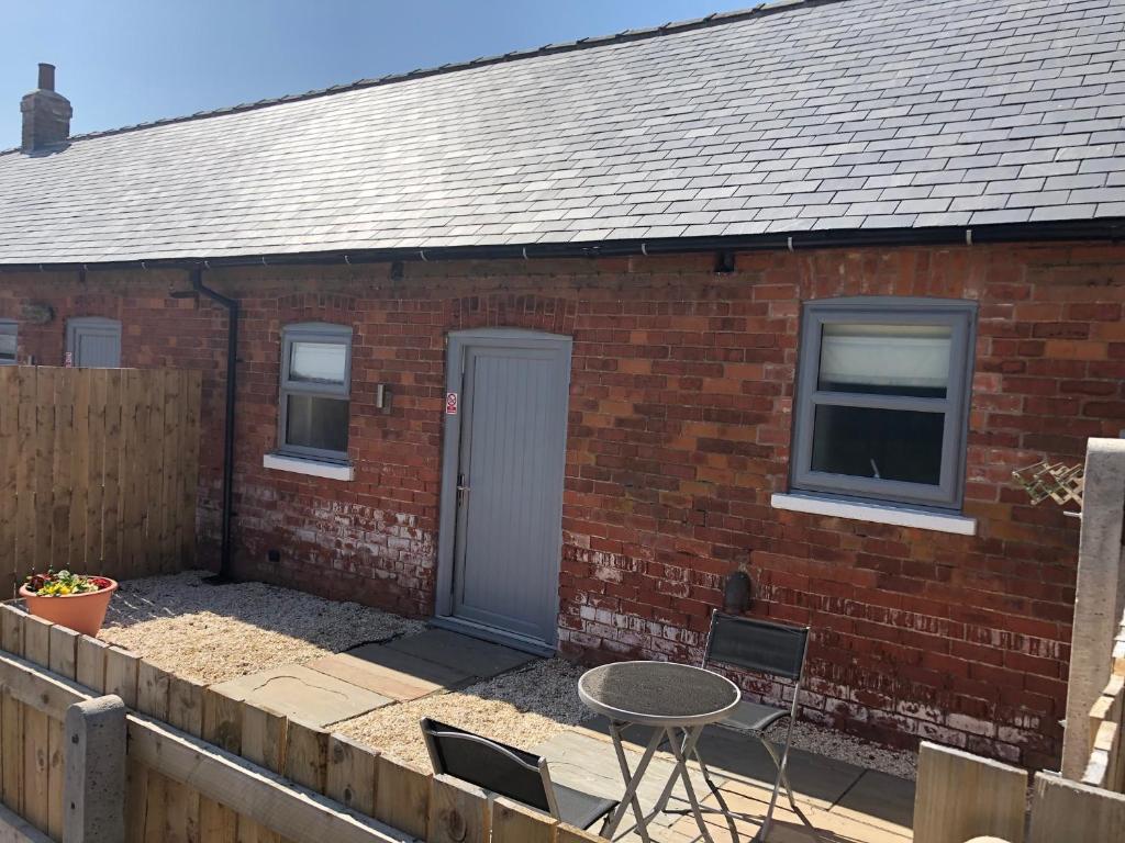 a brick house with a table and chairs in front of it at The Cow 'ouse, Wolds Way Holiday Cottages, 1 bed cottage in Little Weighton