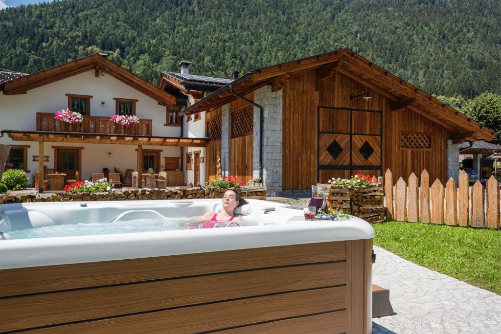 a woman sitting in a bath tub in front of a house at Agriturismo Maso Grisun in Borzago