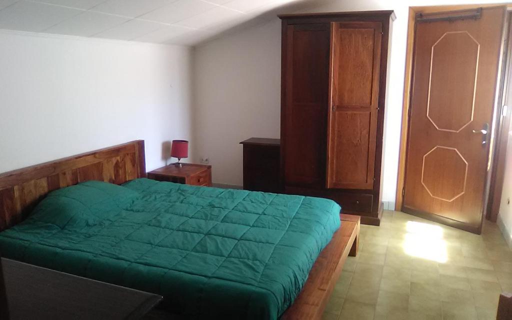 um quarto com uma cama verde e um armário de madeira em Affitta Camere Monte Grappa em Tempio Pausania